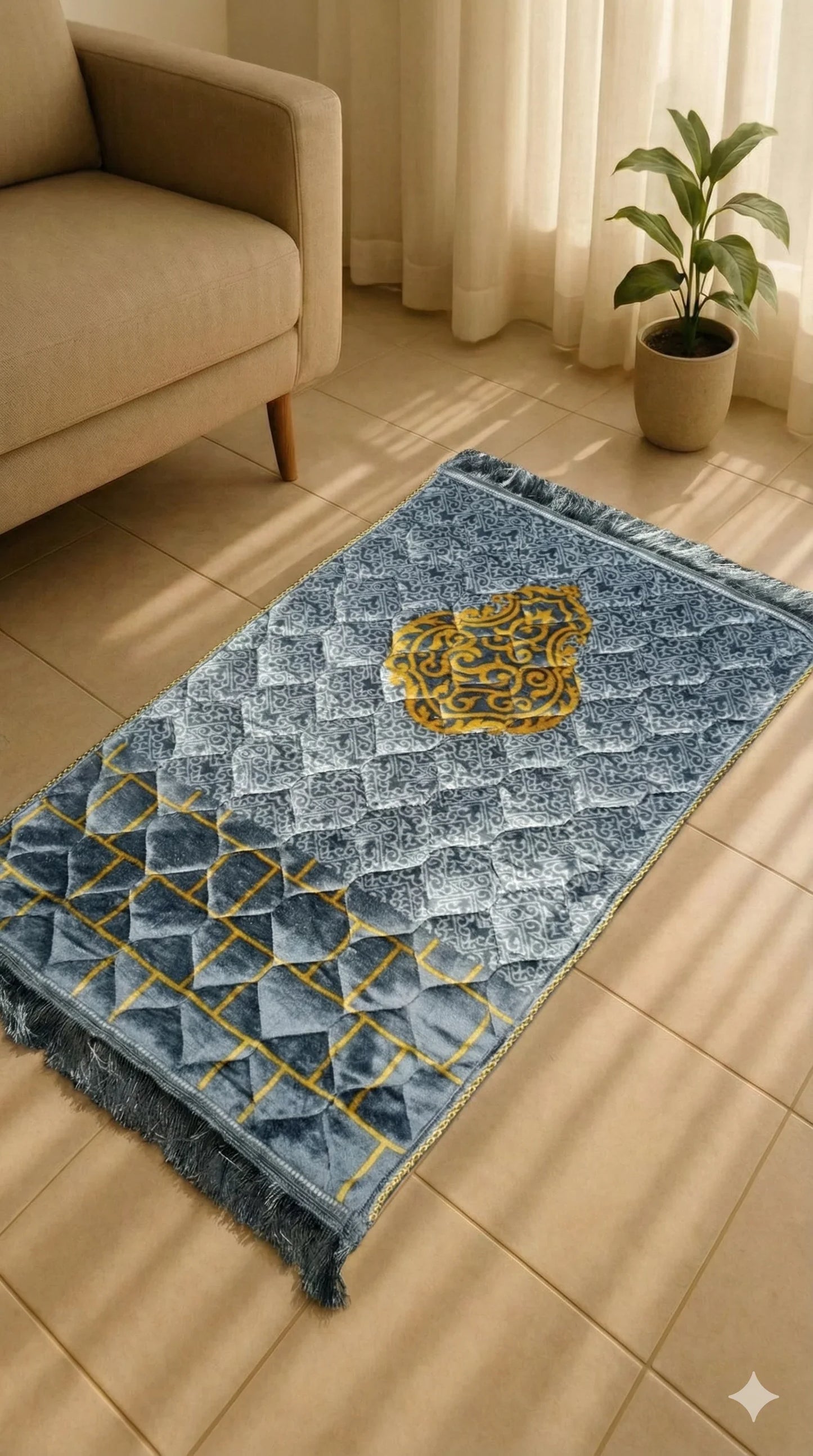 Soft velvet Islamic prayer mat with blue, gray, and gold geometric design on tiled floor next to beige sofa and potted plant