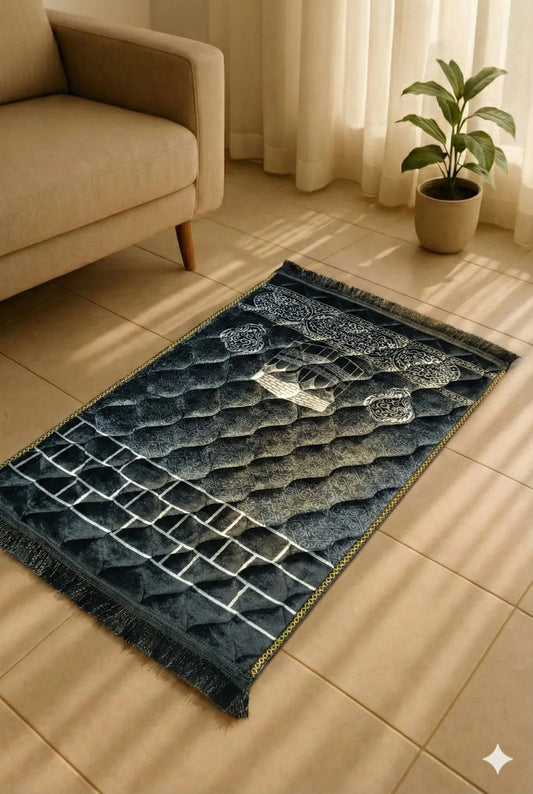 Dark blue Islamic prayer mat with mosque design on tiled floor, beige sofa, and potted plant nearby