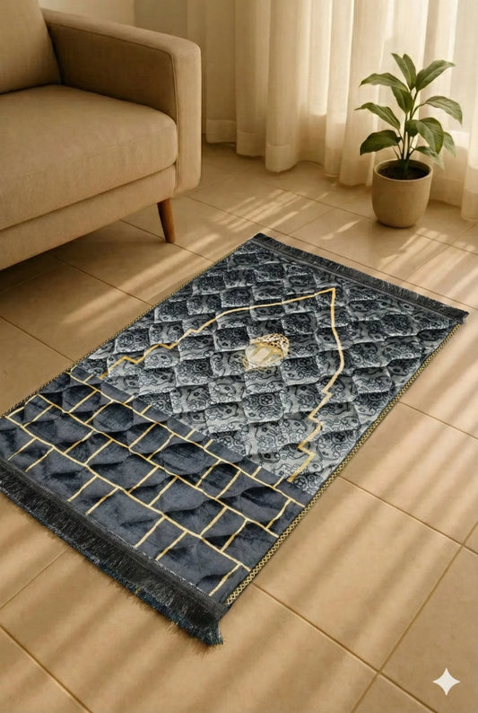 Black and gray Islamic prayer mat with gold geometric details on tiled floor near beige sofa and potted plant