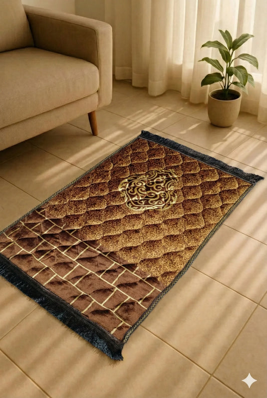 Brown and gold Islamic prayer mat with intricate patterns placed on tiled floor near beige sofa and green potted plant